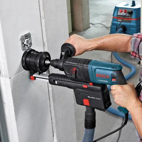Bosch 11250VSRD taladro percutor eléctrico perforando una pared de hormigón, conectado a un sistema de aspiración con "Microfilter System".