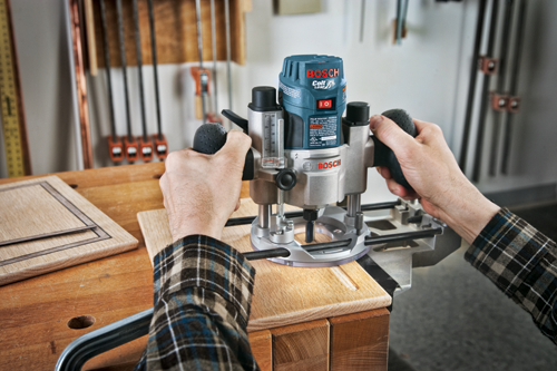 Una persona que utiliza una fresadora de palma Bosch Colt 1.0 HP PR20EVS, con una tensión nominal de 120V-60Hz, 5.7A, 16000-35000 RPM, para fresar una tabla de madera.